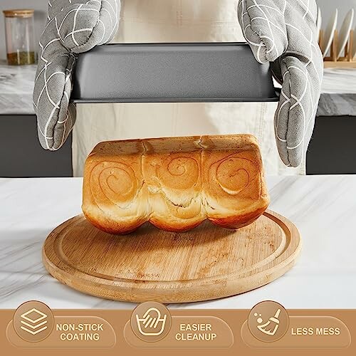 Person with oven mitts holding a baking pan, fresh bread on a round wooden board.