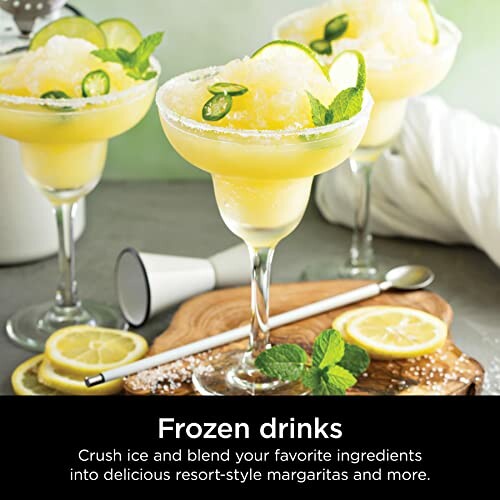 Frozen margaritas with lemon and mint garnish on a table.