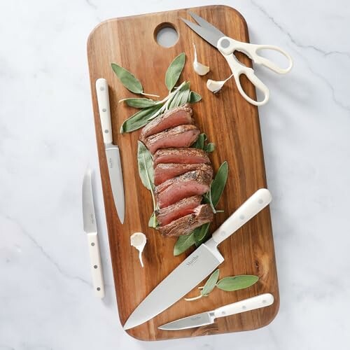 Sliced steak on a wooden cutting board with knives and scissors.